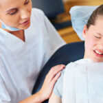 Dental assistant comforting a child suffering from dental anxiety at a pediatric dentist office.