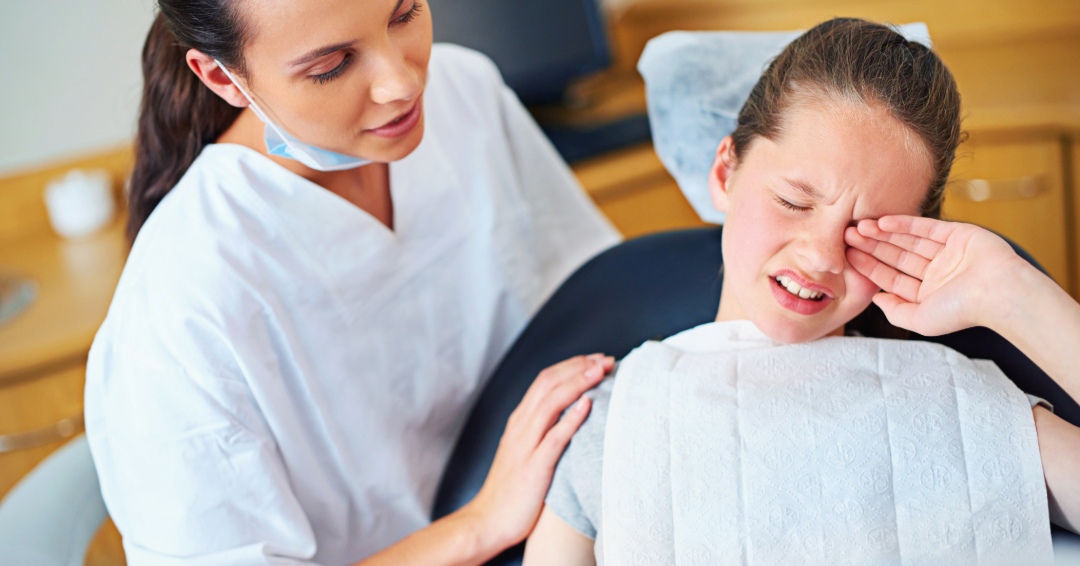 Dental assistant comforting a child suffering from dental anxiety at a pediatric dentist office.