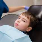 Boy with tooth pain in dentist’s chair.