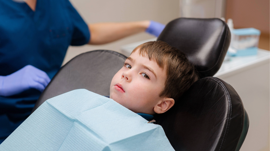 Boy with tooth pain in dentist’s chair.