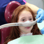 Girl in dentist’s chair receiving sedation dentistry.