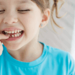 Girl pointing at loose tooth.