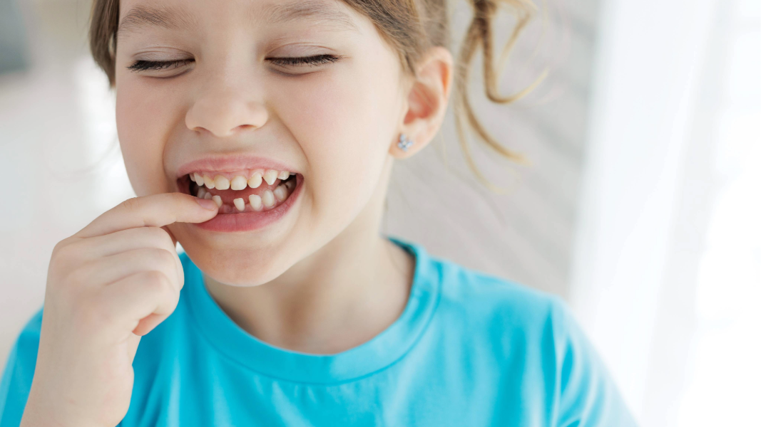 Girl pointing at loose tooth.