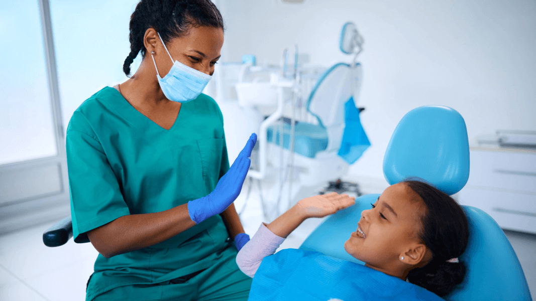 dentist and kid in dental chair high fiving